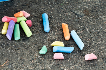 Colored chalk for painting is scattered on the pavement.