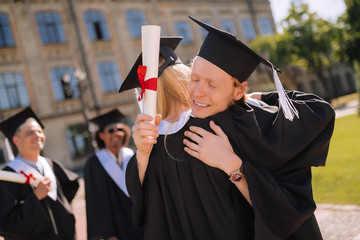Two graduates hugging in front of their university.