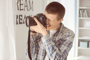 Teenage boy with photo camera at home