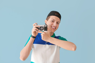 Teenage boy with photo camera on color background