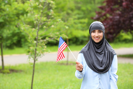 Female Muslim student with USA flag outdoors