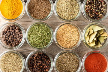 Mix of colourful spices in bowls on wooden table. Collection of seasonings. Top view