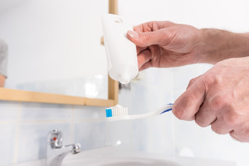 Person putting toothpaste on toothbrush