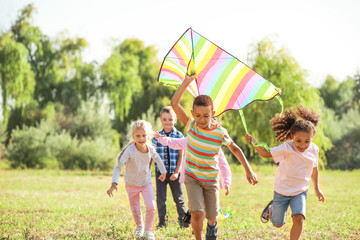 Group of happy children with kite in park - Powered by Adobe