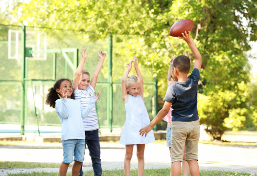 Cute Little Children Playing With Rugby Ball In Park