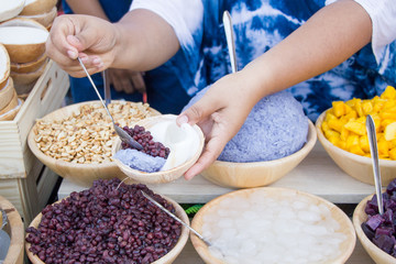 Thai seller put ingredients of cococnut ice cream in coconut shell