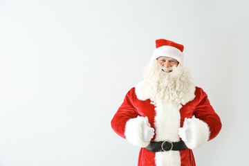 Portrait of Santa Claus showing thumb-up on light background