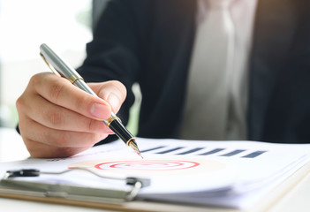 Closeup businessman hand holding pen writing on paperwork.