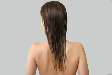 Fototapeta premium Beautiful young woman after washing hair against grey background, back view