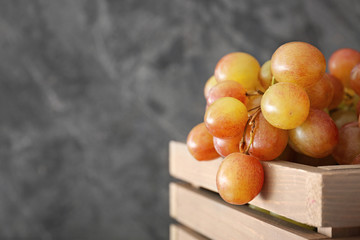 Tasty fresh grapes in box on grunge background, closeup