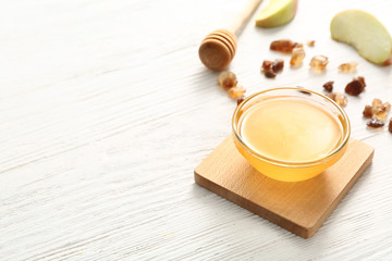 Bowl of tasty honey on wooden background
