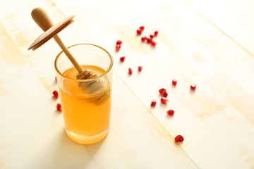 Glass with sweet honey on white wooden background