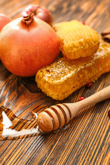Honey dipper, pomegranate and combs on wooden background