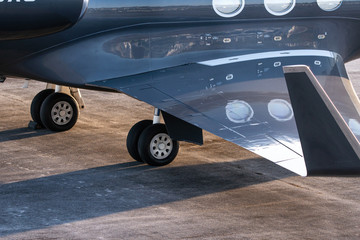 Close up of main lading gear and with wing of big private jet aircraft
