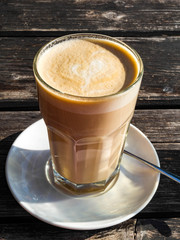 Coffee cafe latte macchiato in a high glass on a wooden background.