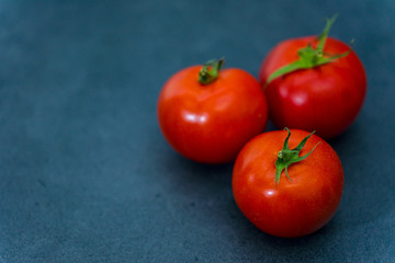 Fresh delicious tomatoes. Red tomatoes on a gray background. Tasty many vegetarian vegetables on a beautiful stone background.