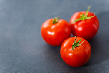 Fresh delicious tomatoes. Red tomatoes on a gray background. Tasty many vegetarian vegetables on a beautiful stone background.