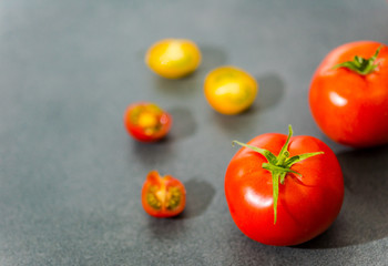 Fresh delicious tomatoes. Red tomatoes on a gray background. Tasty many vegetarian vegetables on a beautiful stone background.