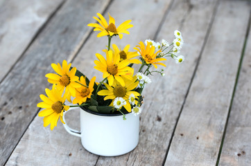 Yellow flowers in old metal cup