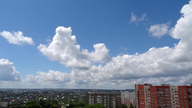 White clouds running over city, bright blue sky. Skyscape timelaps.