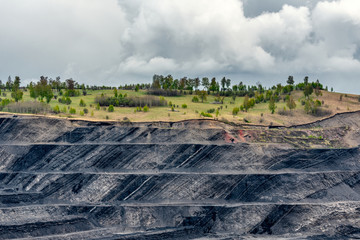 A large quarry with many horizons and ledges. Vertical bedding of coal seams.