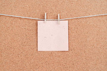 Corkboard with pink color stickers fixed by a pin. Square shaped sheets stuck on a billboard by...