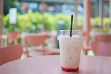 strawberry and milk with ice in transparent plastic glass on pink desk