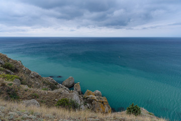 Black Sea coast on a cloudy day with clouds in the sky and a steep mountainside.