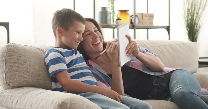 Mother with son having fun while writing shopping list in notepad