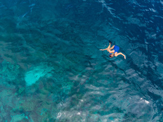 Fototapeta na wymiar Aerial top down people snorkeling on coral reef tropical caribbean sea, turquoise blue water. Indonesia Wakatobi archipelago, marine national park, tourist diving travel destination