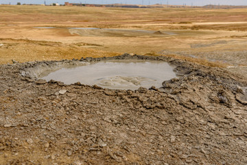 Mud volcano on the Crimean peninsula in sunny weather with clouds on the sky, shot during the season of golden autumn. Yellow-golden brown.