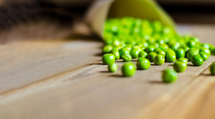 Tasty, green, fresh peas in a paper bag on a wooden background.