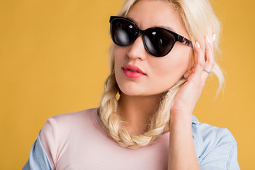 Close up photo of beautiful woman in sunglasses isolated on yellow background