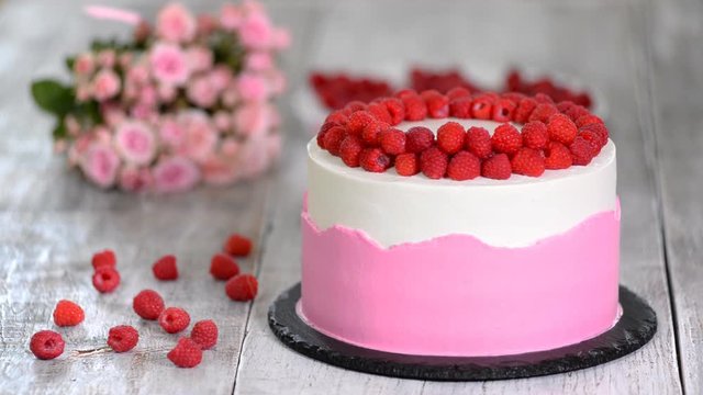 Chef decorate the cake with raspberries.