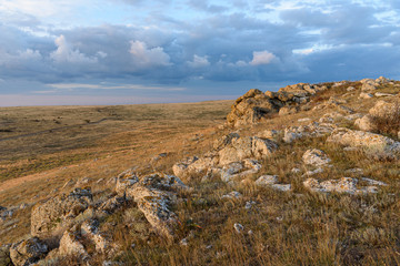 Dawn on a mountain in the steppe of the Opuksky nature reserve with yellow grass, with clouds on the sky, shot during the season of golden autumn. Yellow-golden brown.