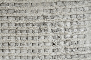 Fototapeta na wymiar Rough grooved gray textured cement wall with pattern prepared for laying tile. Closeup