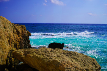 Sea wave breaks on beach rocks in Crete, Greece.