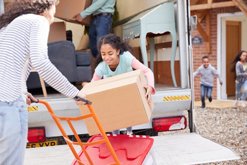 Family Unloading Furniture From Removal Truck Into New Home