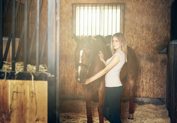 girl hugging a horse in a stable at the ranch.