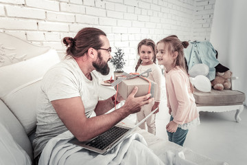 Two small girls surprising their father with birthday present