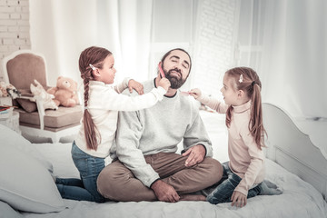 Happy family. Dad and two sisters playing on bed