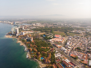 Aerial photos of the beautiful beach and town of Puerto Vallarta in Mexico, the town is on the Pacific coast in the state known as Jalisco with the mountains in the background on a cloudy day.