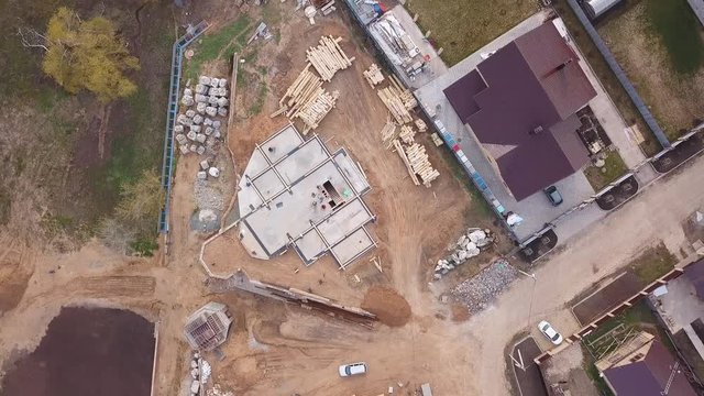 View from above of construction materials ( wooden boards, rocks, bricks) and people working on the building site and pouring concrete. Clip. Process of new building construction