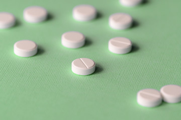 White tablets scattered on a green background close up