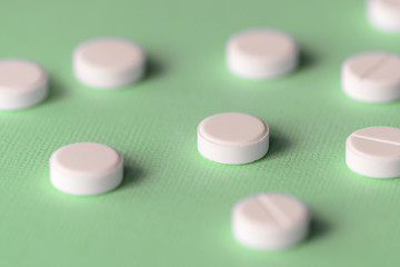 White tablets scattered on a green background close up