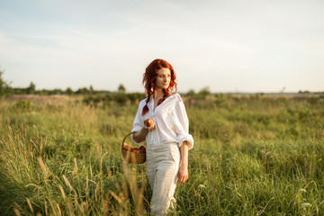 A portrait of a young redhead woman in a summer meadow