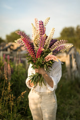 A shy girl hiding behind a bouquet of lupins