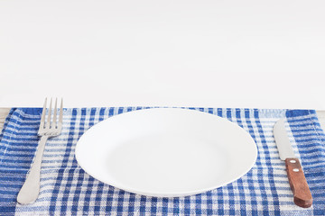 Empty plate on tablecloth or napkin on wooden table over cement background
