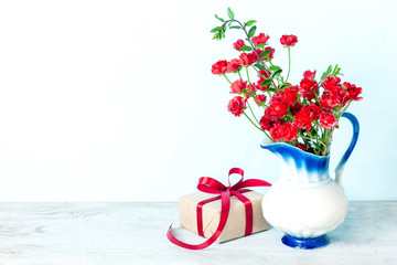 Present or gift box in a craft paper with red ribbon bow on white background. Greeting card for Valentine's or Mother Day.
