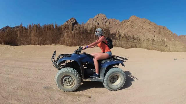 Sexy Girl is Riding a Quad Bike in the Desert of Egypt. Dynamic view in motion.
